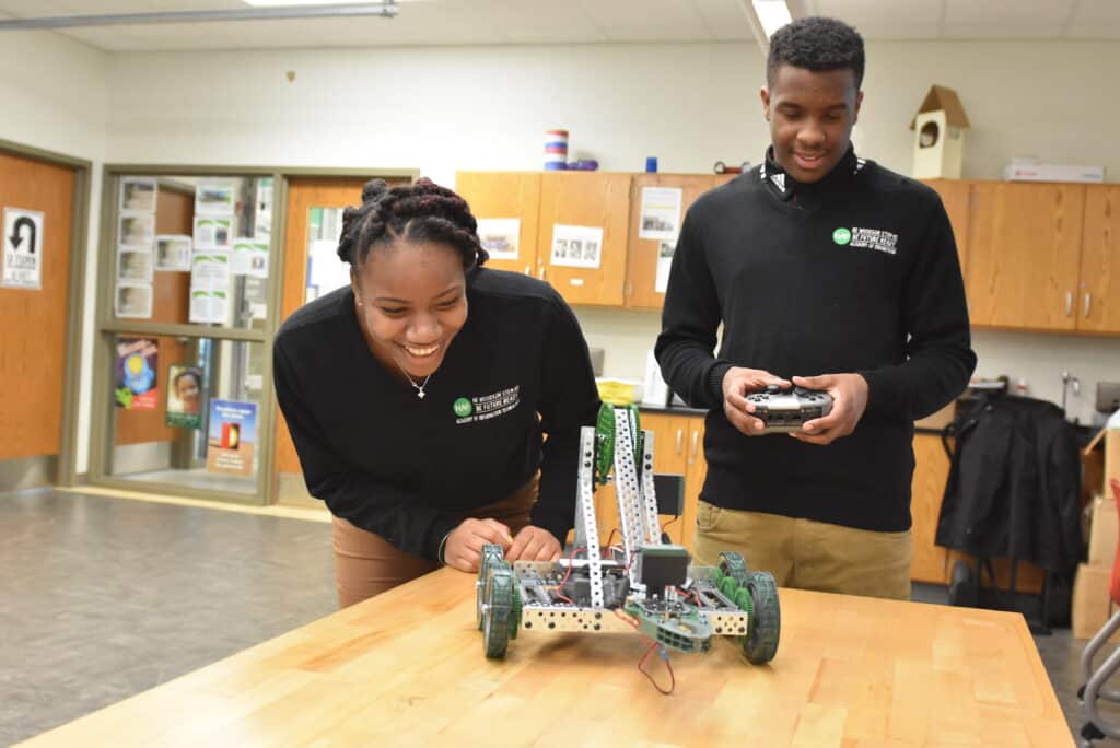 An image showing two H.D. Woodson students operating a robot.